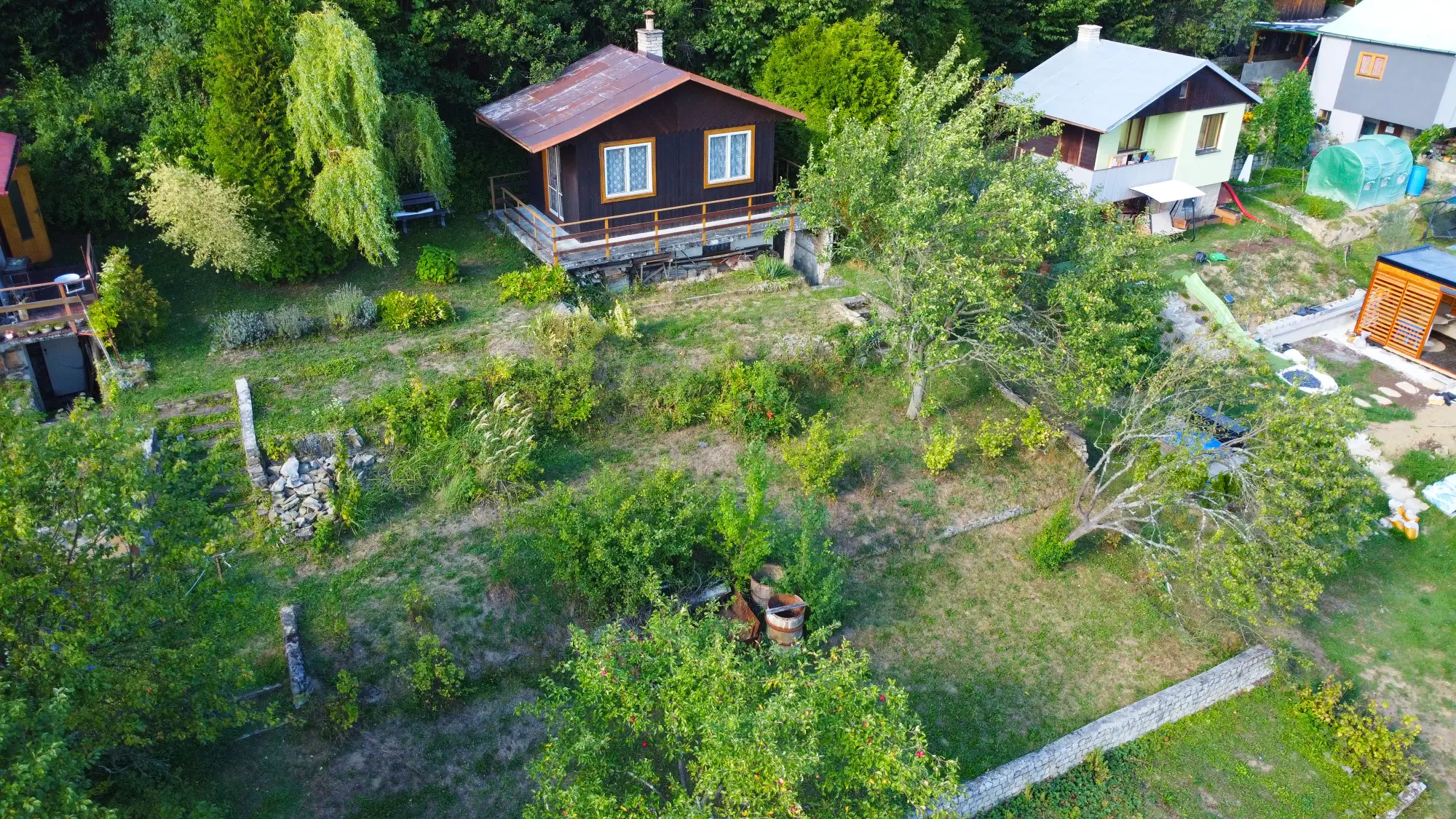 Pohled z dronu na chatu a vzrostlou zahradu v Jasenici