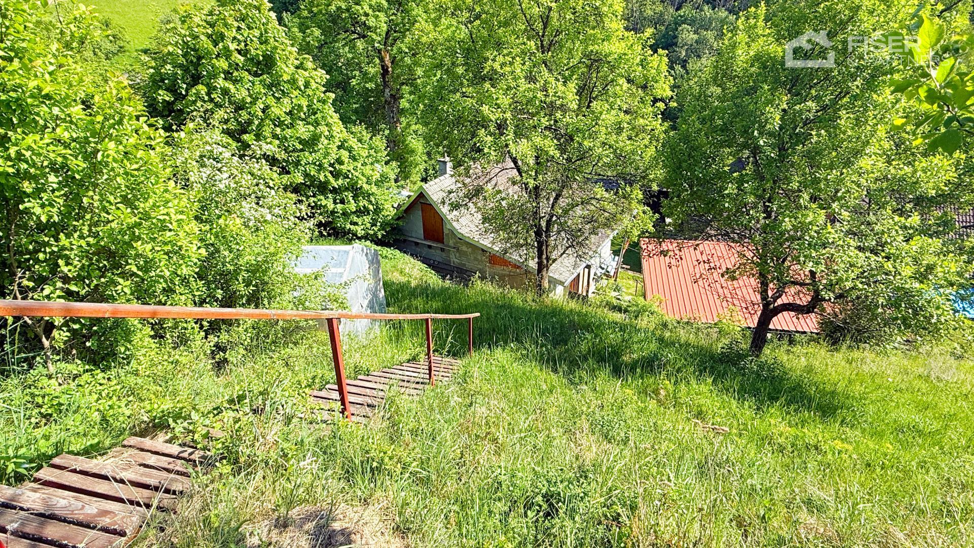 Pohled na chatu zasazenou mezi vzrostlou zeleň