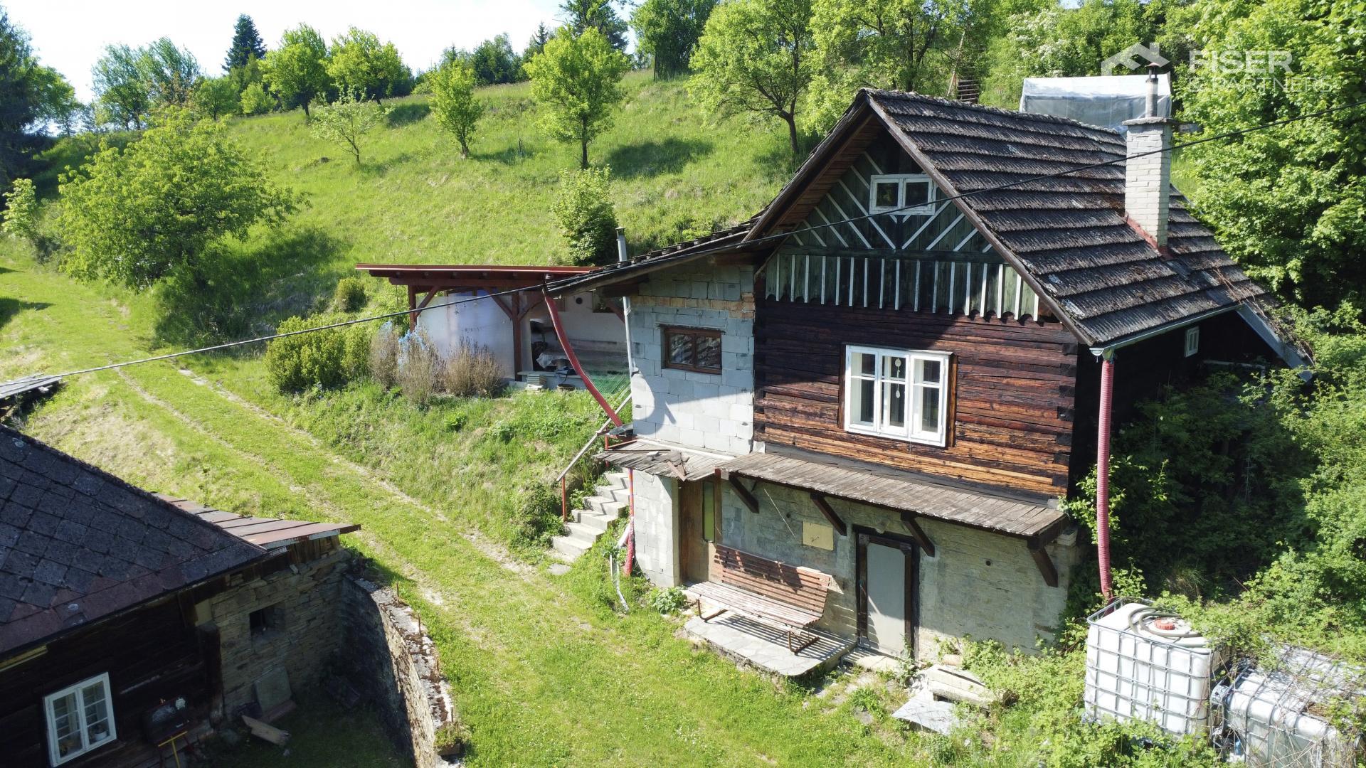 Boční pohled na chatu se zděnou přístavbou a roubenou částí